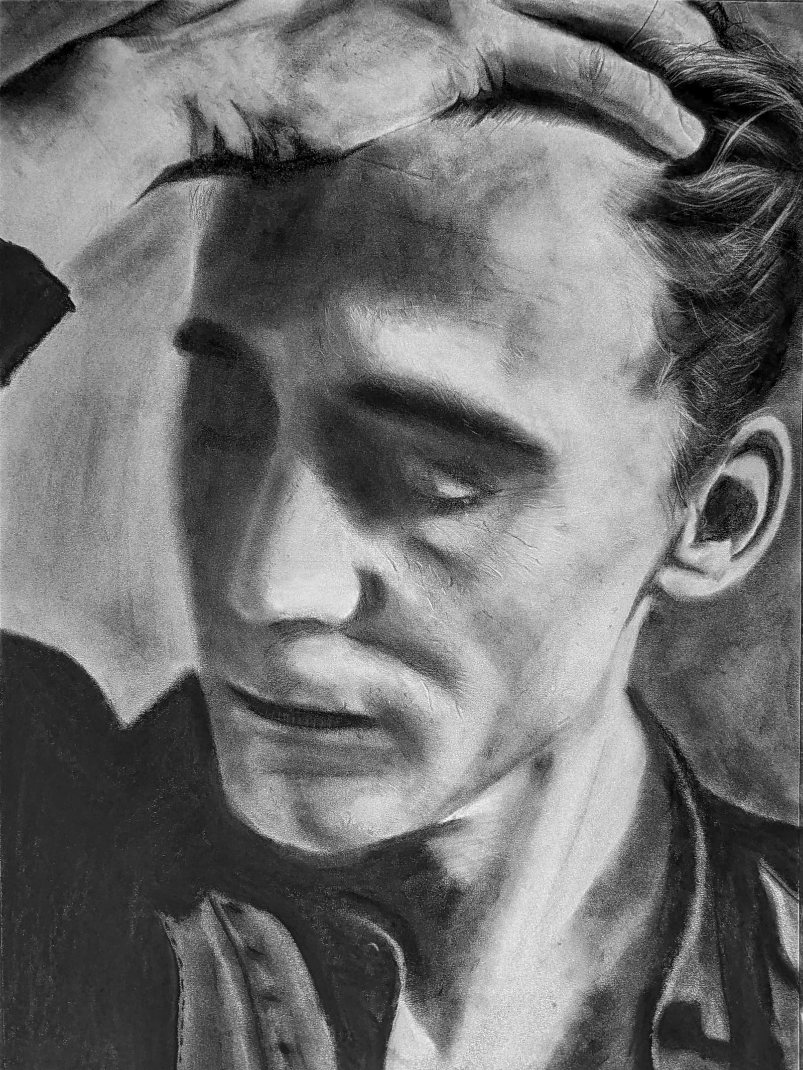 Charcoal portrait of Tom Hiddleston looking down, one hand pushing back his hair